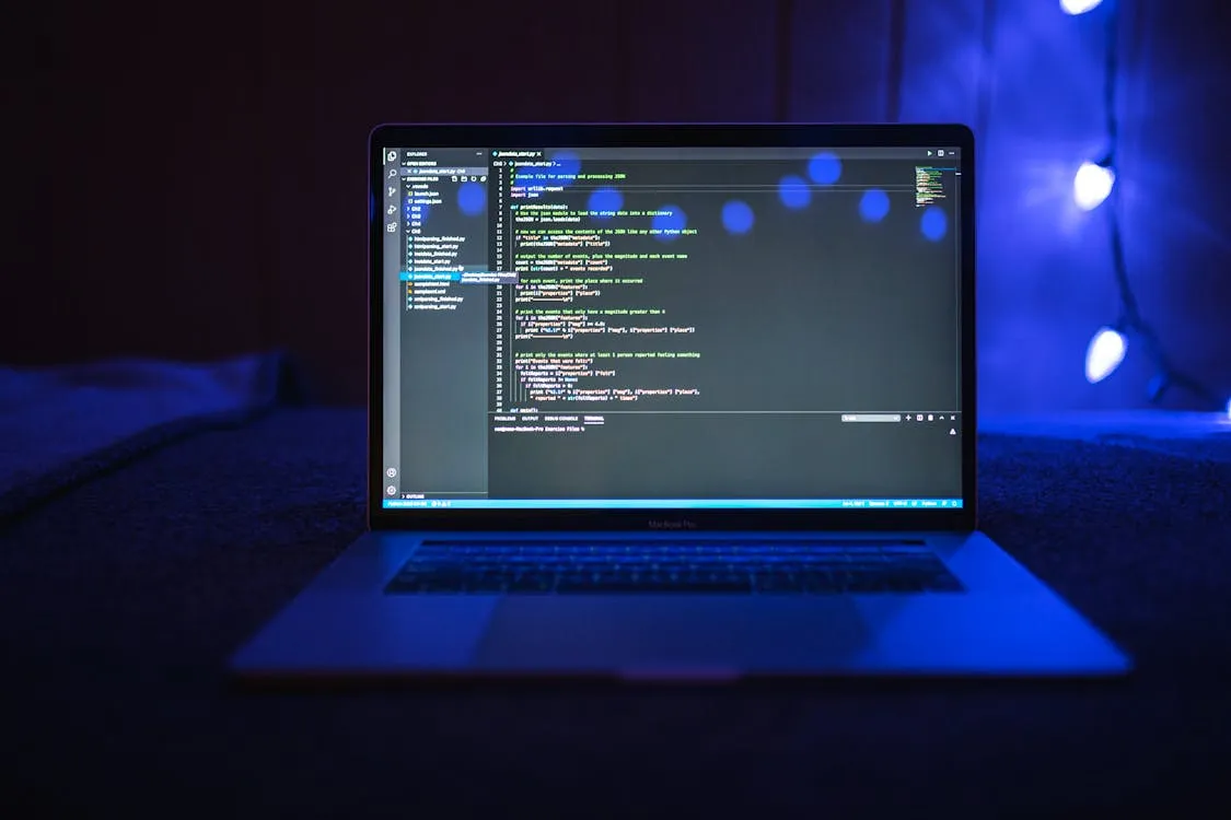 Close-up of programming code displayed on a laptop screen in a dim room, representing agentic coding work.